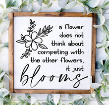 Load image into Gallery viewer, A painted wood sign with a black and white floral design and the text , "A flower does not think about competing with the other flowers, it just blooms".