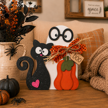 Load image into Gallery viewer, A decorative Halloween tabletop sign featuring a black cat, a white ghost with glasses, and an orange pumpkin, styled on a wooden table with autumn props including a small pumpkin, a spider, dried flowers, and a knitted blanket.
