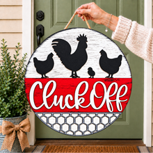 Load image into Gallery viewer, A round decorative hanging sign held by a person's hand in front of a green front door. The sign features black chicken and rooster silhouettes on a distressed white backer, a red banner section with white script reading 'Cluck Off', and a chicken wire pattern at the bottom.