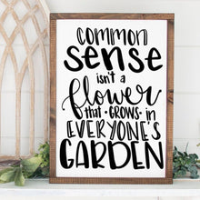 Load image into Gallery viewer, Framed funny rustic handmade sign with text reading Common sense isn't a flower that grows in everyone's garden.

